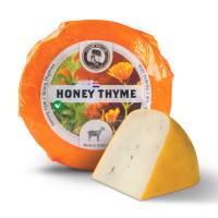 A small goat cheese with honey and thyme in the packaging with a piece of cheese in front of it