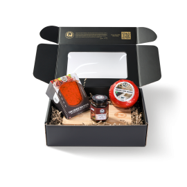 Schwarze Display-Schachtel mit zwei Käsesorten, einem Käsebrett und einem Käse-Dip in der Verpackung.