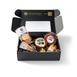 Sechs verschiedene Produkte in einer schwarzen Sichtfenster-Box, darunter Baby-Käse, Käse-Dip und Käsewaffeln.