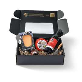 Zwarte display doos met rode wijn fles, baby kaas, kaasstukje en een kaasmesje in de verpakking.
