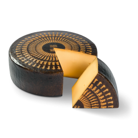 Roue de fromage Bio Pure Gold avec un morceau découpé. Le morceau est devant la roue.