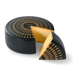 Roue de fromage Bio Pure Perfection avec un morceau découpé. Le morceau est devant la roue.