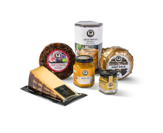 Zwei Baby-Käse, ein Stück Käse, ein Glas Senf, ein Glas Käse-Dip, Käsewaffeln und Feigenbrot in der Verpackung.