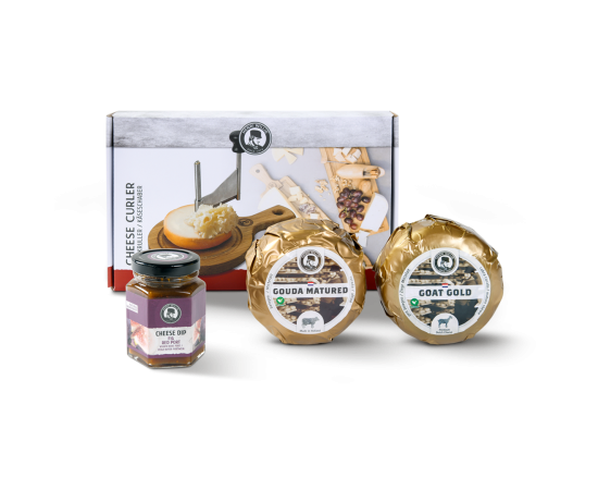 Ein Käseschneider in der Verpackung, zwei Baby-Käse und ein Glas Käsedip.