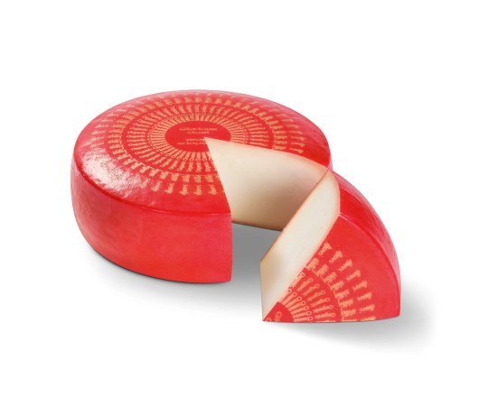 Bio Glorious Goat-Käse rad, ein Stück herausgeschnitten. Das Stück liegt vor dem Rad.