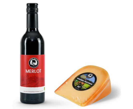 A small bottle of red wine paired with a piece of cheese.