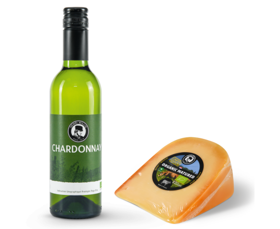 A bottle of white wine with a piece of cheese alongside it.