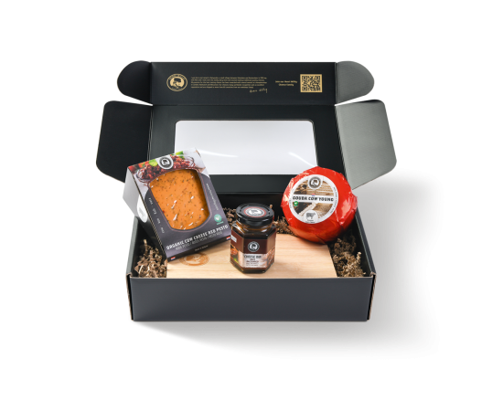 Schwarze Geschenkbox mit zwei Käsesorten, einem Käsebrett und einem Käsedip.