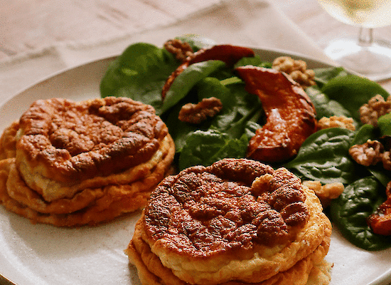 Two cheese soufflés with a salad and a glass of wine.