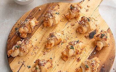 12 mini croissantjes op een ronde houtenplank.