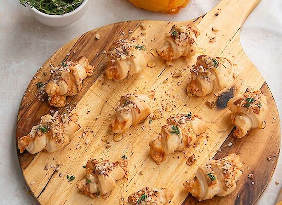 12 mini croissants on a round wooden board.