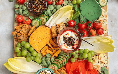 Hot & spicy snack platter with colourful cheeses, grapes, strawberries, cucumber, tomato and dips from Henri Willig