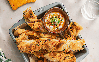 Chili cheese sticks made from puff pastry with fresh yoghurt dip and spicy pine nut butter, golden baked and served as a snack