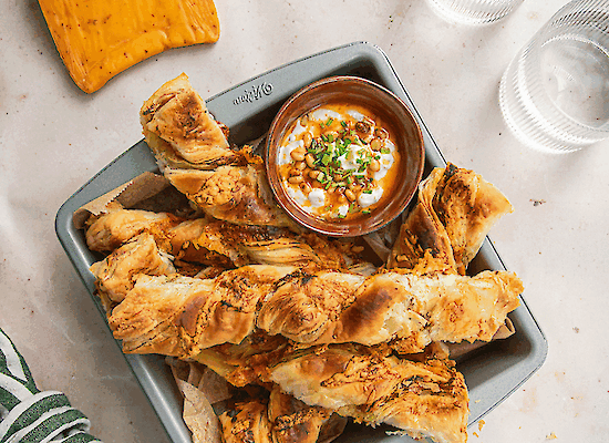 Chili cheese sticks made from puff pastry with fresh yoghurt dip and spicy pine nut butter, golden baked and served as a snack