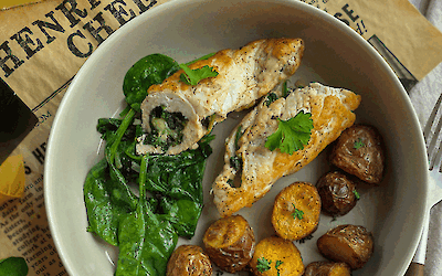 Assiette de roulés de poulet farcis aux épinards et au fromage Henri Willig Jersey, servie avec des pommes de terre grenaille croustillantes et des épinards frais sur du papier fromage Henri Willig Cheese.