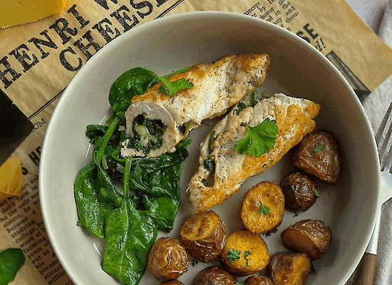 Assiette de roulés de poulet farcis aux épinards et au fromage Henri Willig Jersey, servie avec des pommes de terre grenaille croustillantes et des épinards frais sur du papier fromage Henri Willig Cheese.